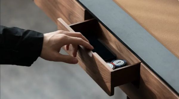 Hand opening a chip drawer in the black walnut frame of an automatic mahjong table