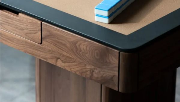 Close-up of the black walnut frame corner and leather top edge of a mahjong table